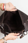 A close-up of a person's hands holding open a dark brown Gucci shoulder bag, showing the interior lining and interior pocket. The bag features the classic GG monogram pattern and silver-tone hardware.