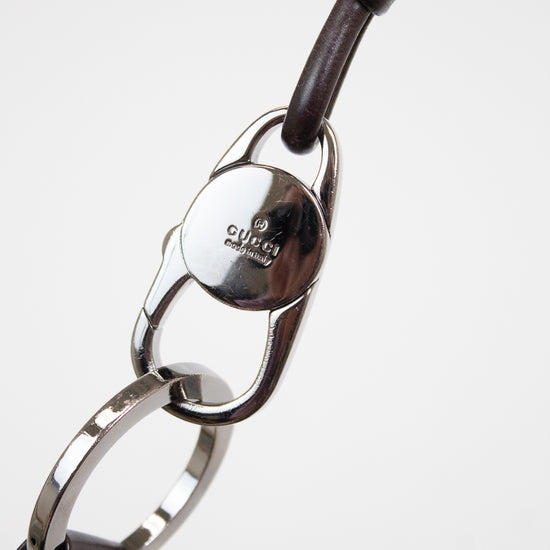 Close-up of a Gucci strap with dark brown leather and a polished silver-tone metal clasp on a white background.