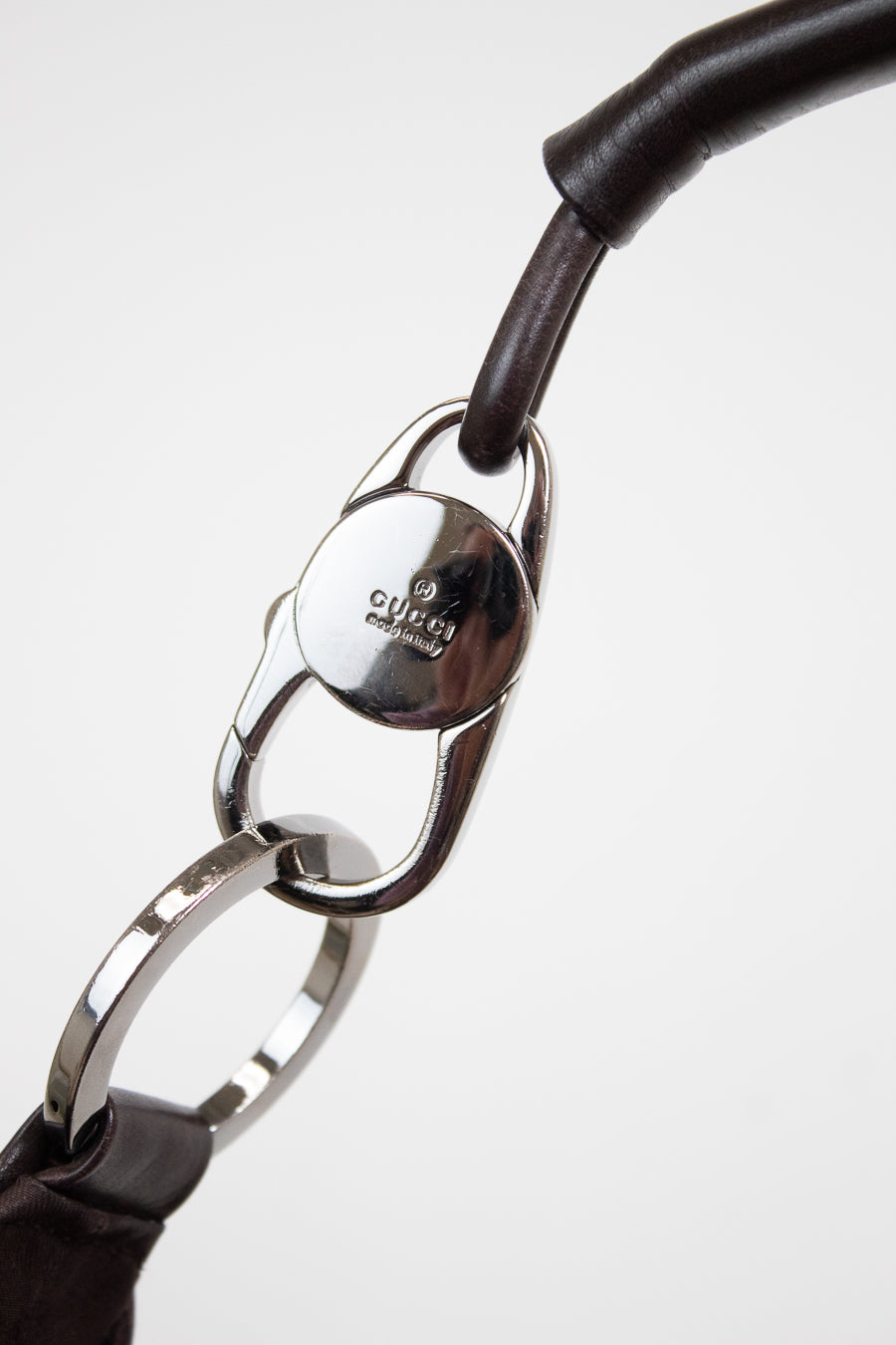 Close-up of a Gucci strap with dark brown leather and a polished silver-tone metal clasp on a white background.