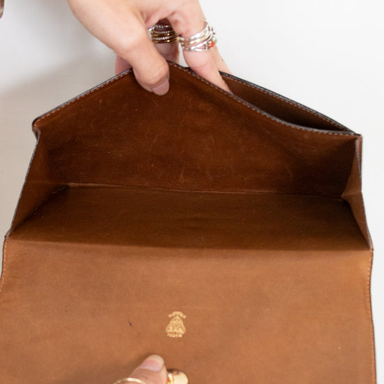 Two hands opening clutch purse showing the interior