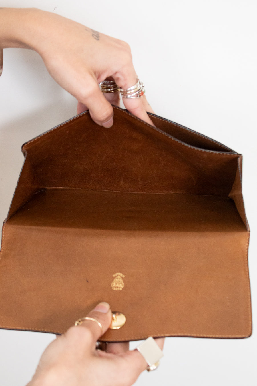 Two hands opening clutch purse showing the interior