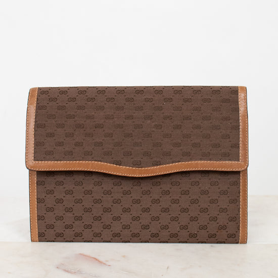 Brown Gucci monogram clutch purse on a white marble surface
