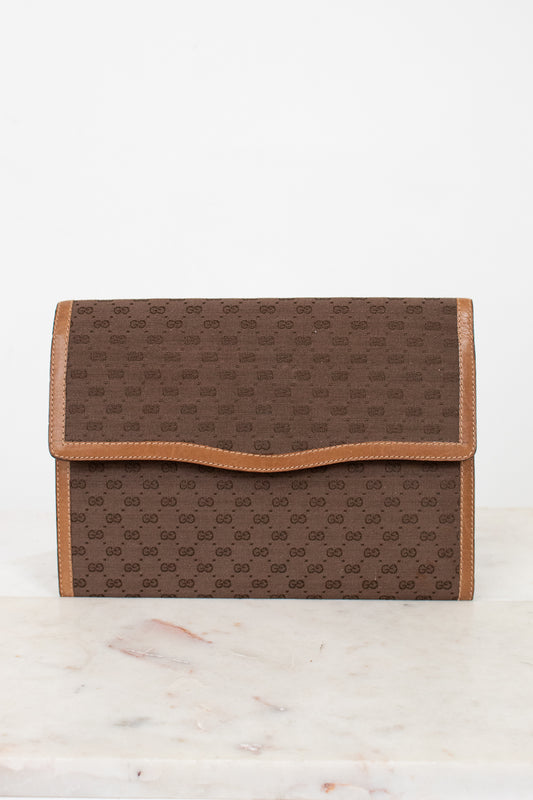 Brown Gucci monogram clutch purse on a white marble surface