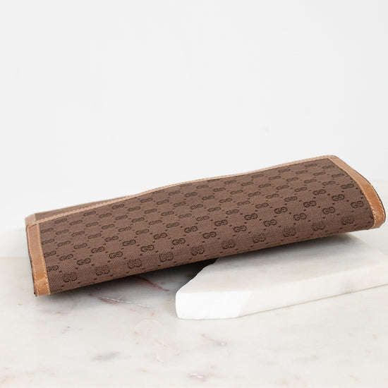 Brown Gucci monogram rectangular clutch purse on a white marble surface