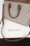 A Gucci handbag in beige and brown GG Supreme canvas with brown leather handles and shoulder strap, displayed on top of a white Gucci box.