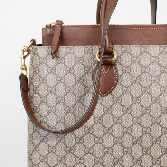 Gucci monogram canvas handbag with brown leather trim and handles, gold-tone hardware, and a detachable shoulder strap, shown on a clean white background.