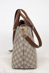 A Gucci handbag in beige and brown GG Supreme canvas with brown leather trim and gold-tone hardware, shown from the side against a plain white background.