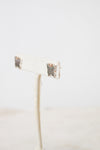 A side profile view of a silver butterfly studs from GUCCI  resting on a beige earring stand.