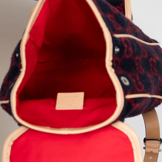 Red interior of a patterned bag with a beige strap.