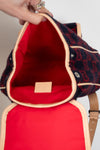 Red interior of a patterned bag with a beige strap.