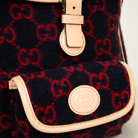 Black backpack with red pattern and beige accents on a light gray background