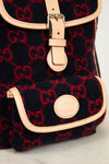 Black backpack with red pattern and beige accents on a light gray background