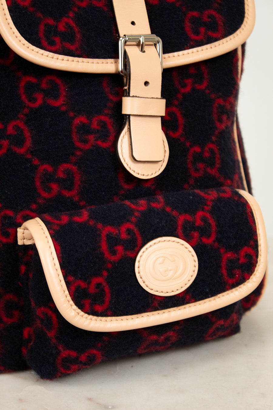 Black backpack with red pattern and beige accents on a light gray background