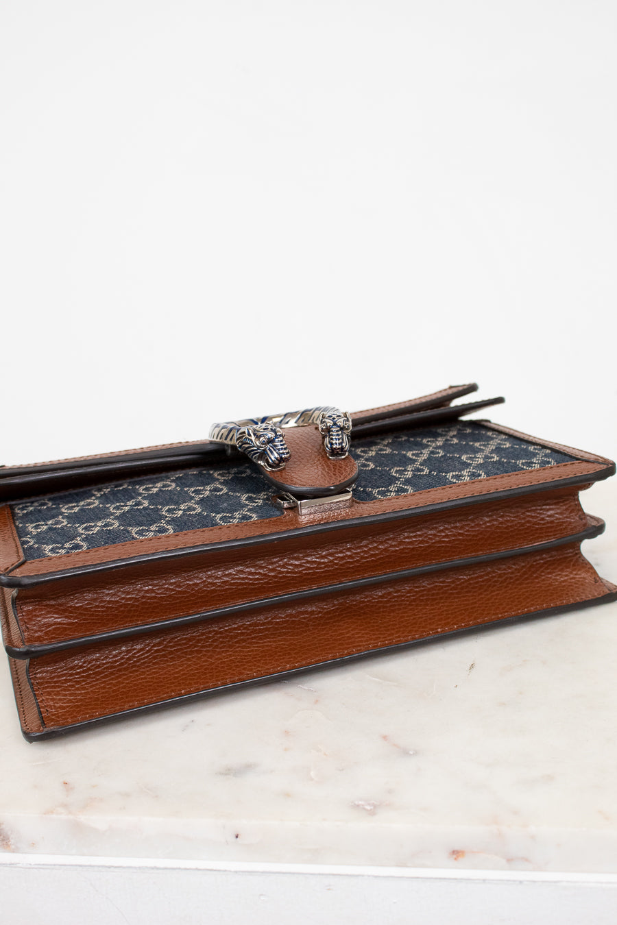 Gucci patterned handbag with brown leather details on a white surface