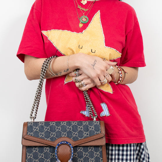 Person wearing a red shirt with a yellow star design, holding a Gucci handbag.