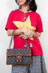 Person wearing a red shirt with a yellow star design, holding a Gucci handbag.