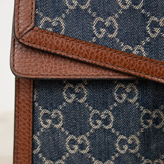 Close-up of a blue fabric bag with brown leather trim featuring a "GG" pattern.