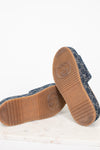 A pair of Gucci platform slip-on shoes shown from the bottom, featuring a navy blue monogram denim upper and a brown rubber sole with an embossed Gucci logo.