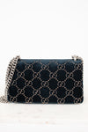 A dark teal blue velvet Gucci shoulder bag with the signature GG monogram pattern in beige, featuring a silver-tone chain strap.