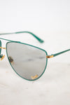 Close up of teal aviator frame with gold 'Gucci' brand detail on gray lens