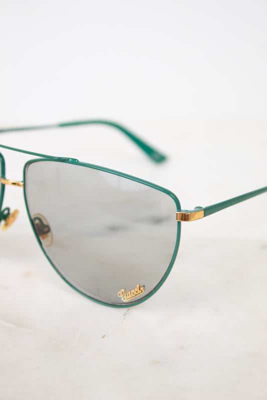 Close up of teal aviator frame with gold 'Gucci' brand detail on gray lens