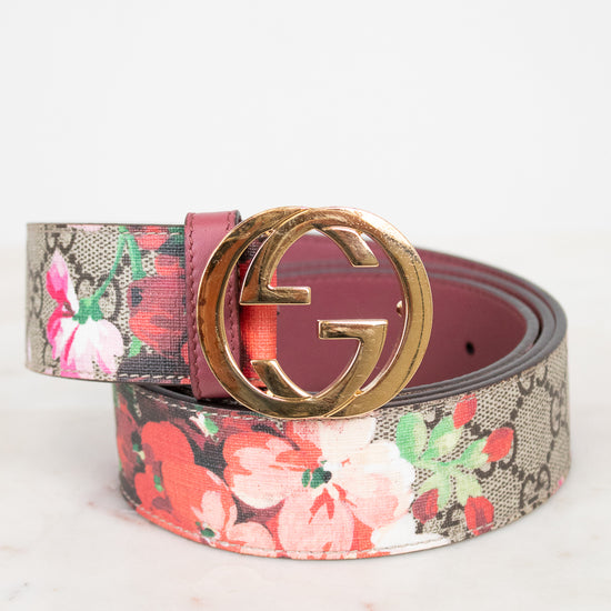 A Gucci belt featuring a pink and red floral print over the brand's signature GG monogram canvas, finished with a polished gold-tone interlocking G buckle.