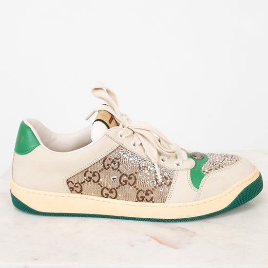 A Gucci low-top sneaker in beige suede and GG Supreme canvas, embellished with rhinestones on the toe box, featuring green heel and outsole accents.