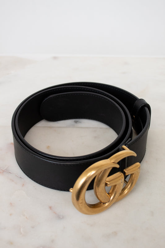 Black belt with a gold buckle on a marble surface