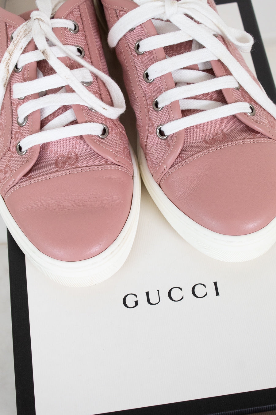 Pink Gucci sneakers with white laces on a Gucci box.