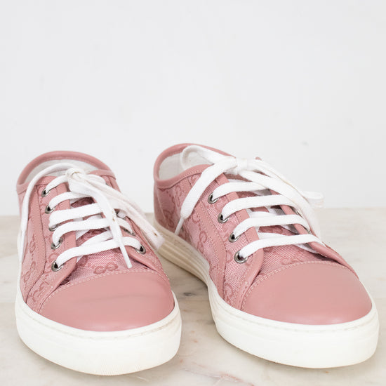 Pair of pink sneakers with white laces on a light background