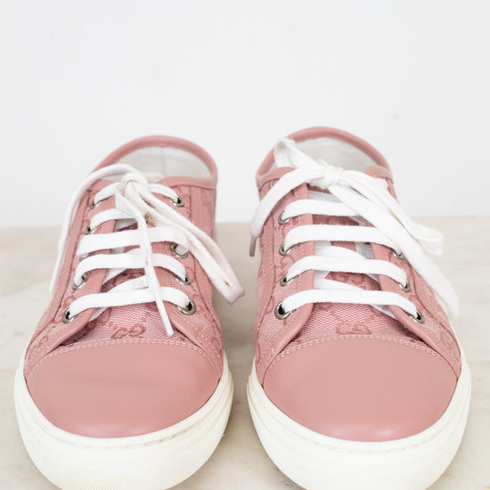 Pair of pink sneakers with white laces on a light background