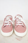 Pair of pink sneakers with white laces on a light background
