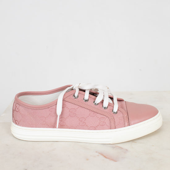 Pink sneaker with white laces on a light gray background
