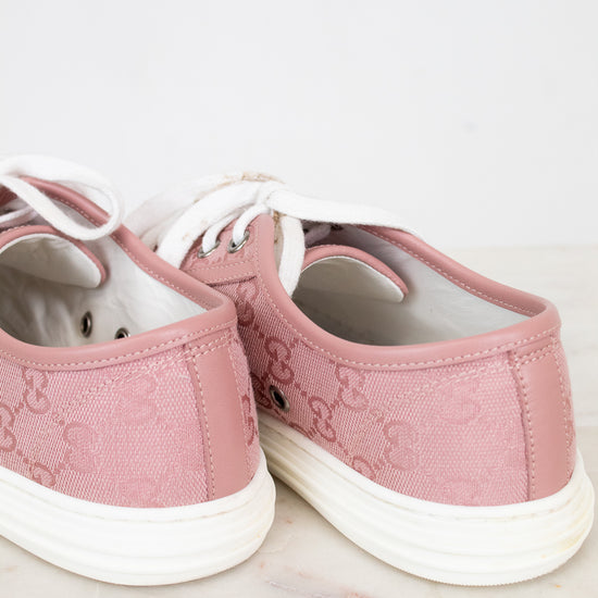 Pair of pink sneakers with white soles on a light background