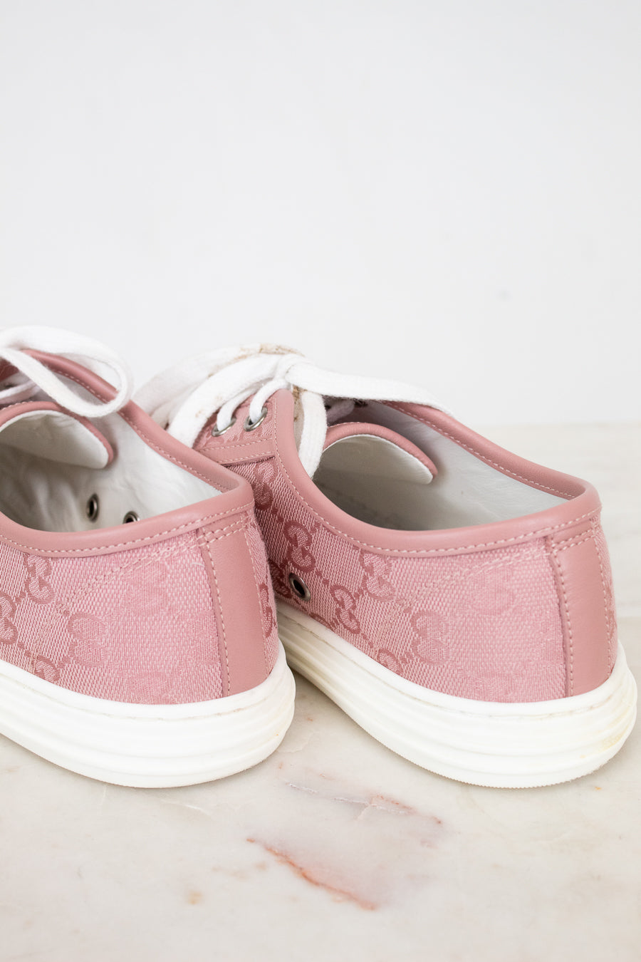 Pair of pink sneakers with white soles on a light background