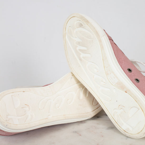 Close-up of white soles of pink sneakers on a marble surface with a light gray background