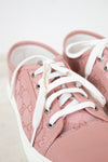 Pink sneakers with white laces on a light background