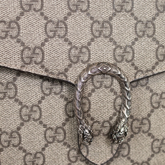 Close-up of a Gucci monogram coated canvas clutch bag with a silver-tone Dorothea buckle clasp on a light marble surface.