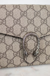 Close-up of a Gucci monogram coated canvas clutch bag with a silver-tone Dorothea buckle clasp on a light marble surface.