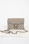 A beige and brown GG Supreme coated canvas shoulder bag with a silver-tone chain strap, displayed on a white marble surface against a white background.
