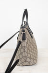 A beige and brown GG Supreme canvas handbag with black leather trim, handles, and shoulder strap, shown from a side profile view on a light background.