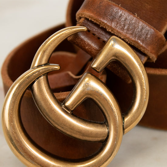 Brown leather belt with a gold buckle on a light background