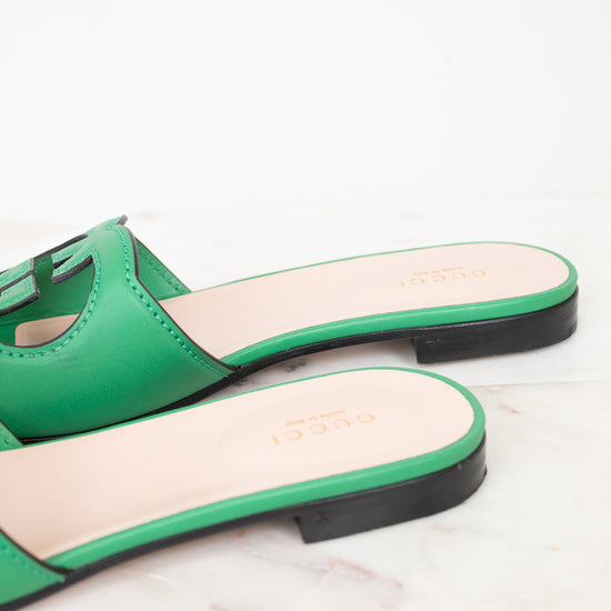 Side back view of green leather GG slides showing black heel detail and displayed against a marble surface