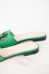 Side back view of green leather GG slides showing black heel detail and displayed against a marble surface