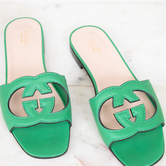 Green leather GG slides shown against a marble surface