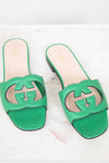 Green leather GG slides shown against a marble surface