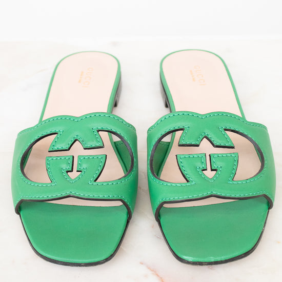 Green leather GG slides shown against a marble surface