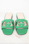 Green leather GG slides shown against a marble surface