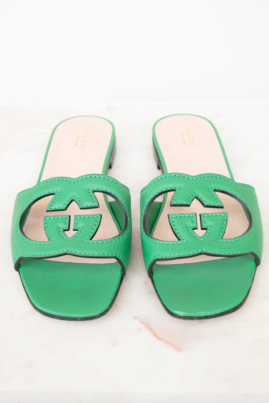 Green leather GG slides shown against a marble surface