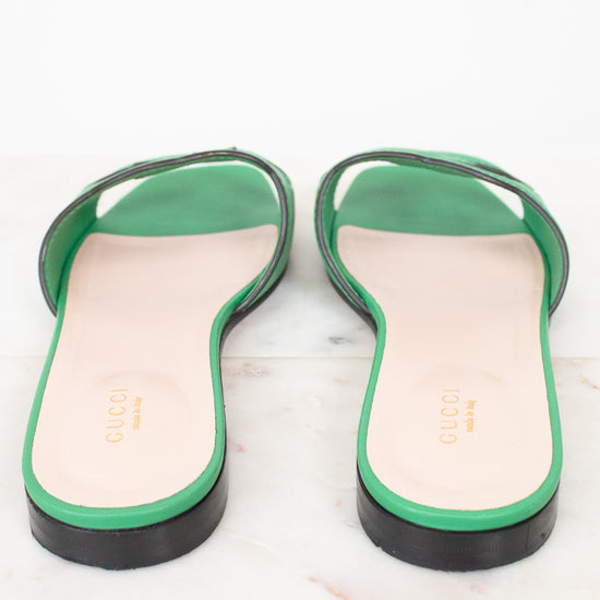 Heel view of green leather GG slides showing black heel detail and displayed against a marble surface